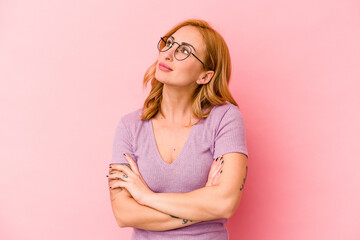 Young caucasian woman isolated on pink background dreaming of achieving goals and purposes