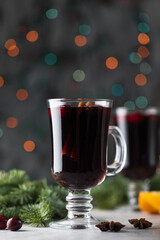  Glasses with homemade mulled wine on a Christmas background with branches of a Christmas tree, cranberries and bokeh.