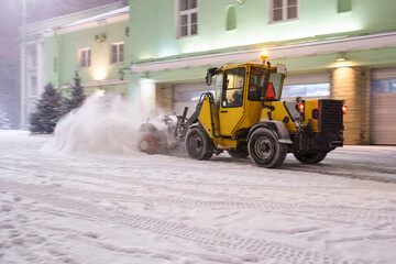 Tractor cleaning snow from road after snowfall and blizzard in city. Snowblower working on street...