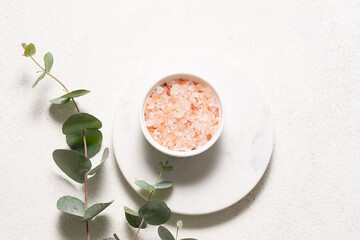 Pink Himalaya salt and fresh aromatic eucalyptus branches on white marble podium top view. Spa and wellness composition.