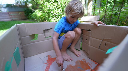 Artistic Little boy inside cardboard box painting