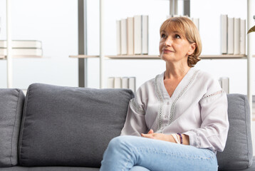 portrait senior woman smiling and looking something on sofa