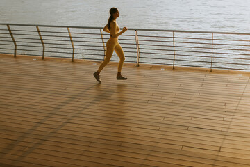 Young woman running on the riverside pier