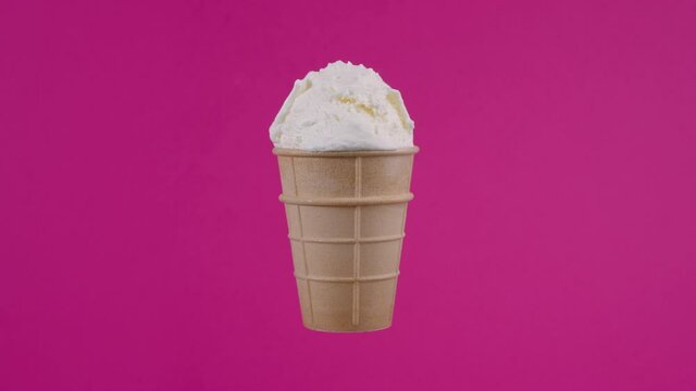 Tasty vanilla ice cream in waffle cone. Sweet dessert, rotating soft cream, gelato icecream scoop over red background