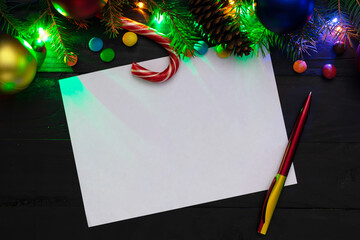 Christmas back,ground, green fir branches, red and blue , yellow balls, candies, cone, garland, white sheet and a pen, black boards