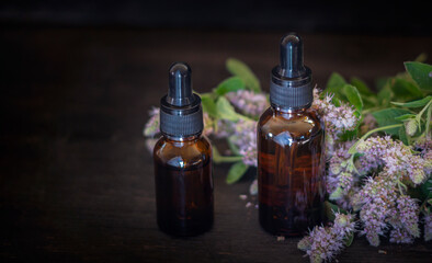 dropper bottles with mint oil made of glass and mint flowers on a black background