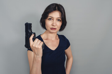 Pistol in hands of  woman. Short black hair. Concept of violence.