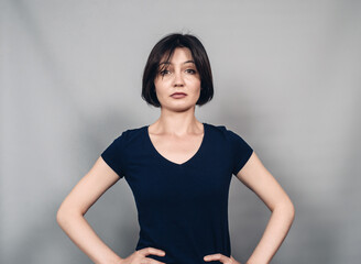 Portrait of beautiful woman with black short  hair. Hands on hips. Looking at the camera.