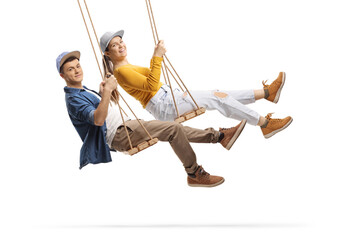Profile shot of a guy and girl swinging on wooden swings and smiling