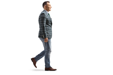 Full length profile shot of a young man in jeans and stylish suit walking