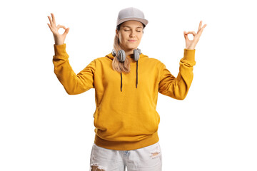 Young female listening to music on headphones and meditating