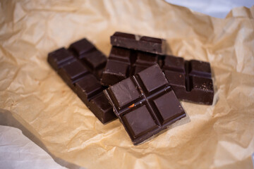 A bar of dark chocolate lies on the paper