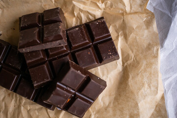 A bar of dark chocolate lies on the paper
