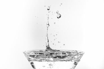 Close-up of water drop falling into a glass on white background