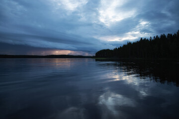 Fototapeta premium Lake under dark storm clouds. Rainy weather landscape.