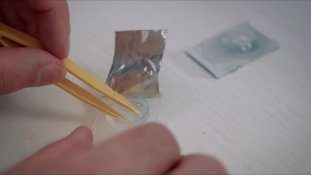 Man take contact lenses from holding plastic container. Vision correction of myopia, hyperopia concept.