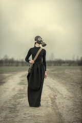 A woman in a gas mask in a black dress is saving from an epidemic, chemical pollution or war after...