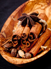 Cinnamon sticks and spieces close up on wooden table. Dark style