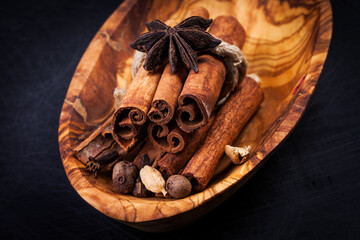 Cinnamon sticks and spieces close up on wooden table. Dark style