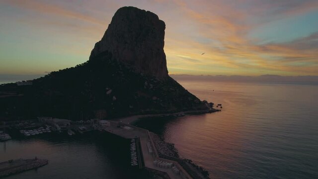 Aerial shot, drone point of view Penyal d Ifac Natural Park rocky cliff surrounded by calm Mediterranean Sea water during picturesque sunrise. Province of Alicante, Costa Blanca. Spain. Travel concept