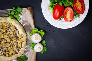 Pie with stewed potatoes and mushrooms on black background