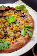 Pie with stewed potatoes and mushrooms on black background