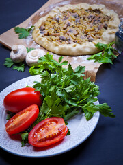 Pie with stewed potatoes and mushrooms on black background