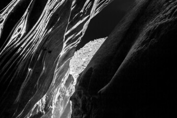 Ice cave of the Bogdanovich glacier - inside view. Ice, daylight. December, Kazakhstan. Black and white image