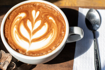 Hot coffee latte art in cup on wooden table.