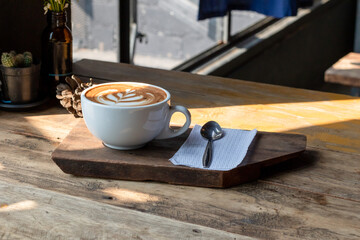 Hot coffee latte art in cup on wooden table.