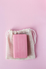 Natural pink soap with a bag on a pink background