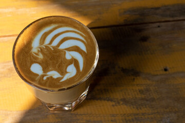 Hot coffee latte art in cup on wooden table.