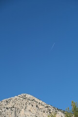 a plane on blue sky behind of cliff on far away