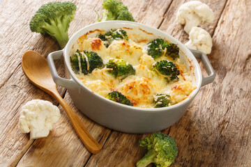 Cheesy creamy Broccoli Cauliflower Casserole close up in the dish on the old table. Horizontal