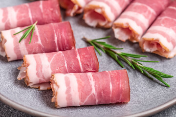 Raw smoked bacon roll with rosemary close-up. Selective focus. Side view