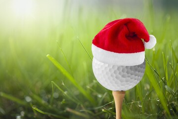 Festive-looking golf ball on tee with Santa Claus' hat on top for the holiday season on golf course...