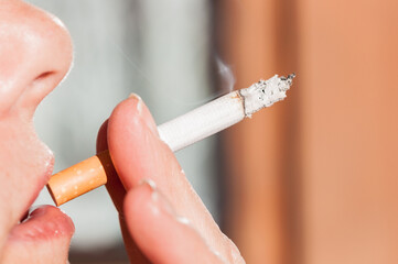 smoking woman: close-up of a woman's lips with a smoking cigarette between the fingers
