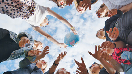 Female student girls standing in a circle toss the world globe up.