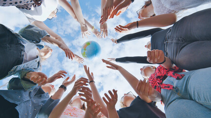 Female student girls standing in a circle toss the world globe up.