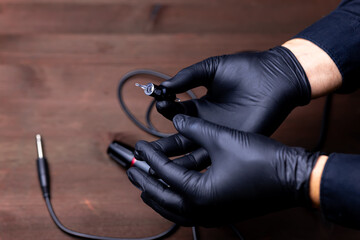 the hands of the permanent makeup artist in black medical gloves pulled a disposable cartridge out...