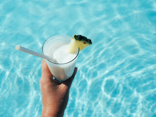Beautiful glass with a refresh cocktail and a pretty woman on the background of the swim pool. Top view, close-up. Vacation and travel concept. Moments of celebration - obrazy, fototapety, plakaty