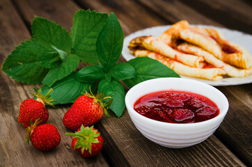 strawberry jam in a bowl. Breakfast. summer composition on a wooden table.