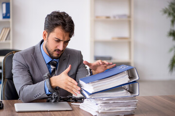 Young chained male employee sitting in the office