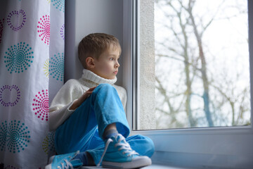 Sad face of a child, 7 years old boy, at home by the window. - obrazy, fototapety, plakaty