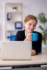 Young female employee drinking coffee during break