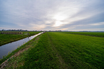An autumn landscape of a farm ditch between the meadows
