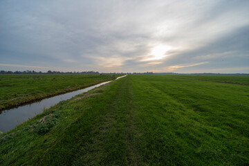 An autumn landscape of a farm ditch between the meadows
