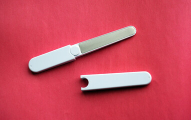 white sharp steel nail file on pink background