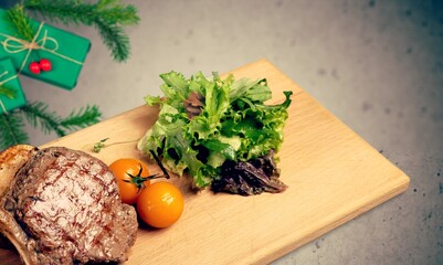 Christmas dinner for two, grilled beef steak, ribeye, greens and spices with a Christmas tree