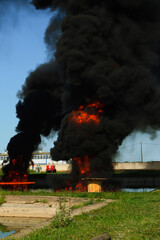 A giant high fire with black smoke of burning oil. The flame is explosive large and firefighters.